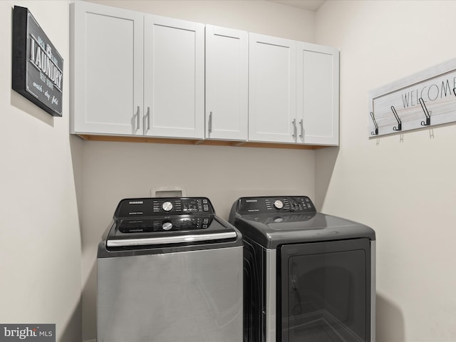 clothes washing area featuring washing machine and dryer and cabinets