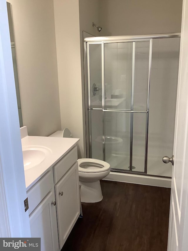 bathroom featuring walk in shower, vanity, wood-type flooring, and toilet