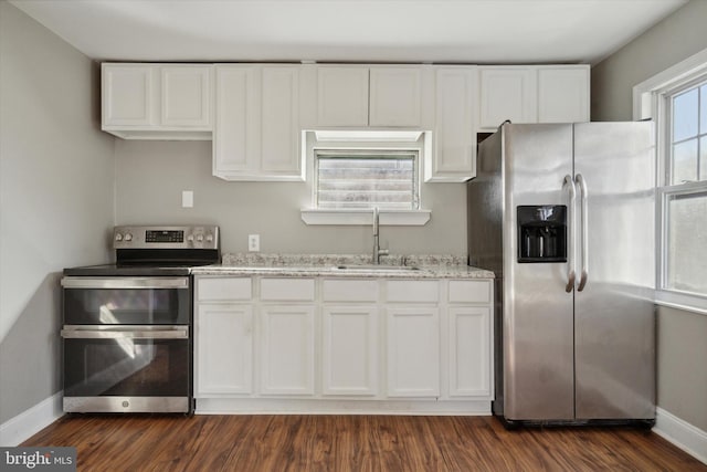 kitchen with light stone counters, stainless steel appliances, dark wood-type flooring, sink, and white cabinetry