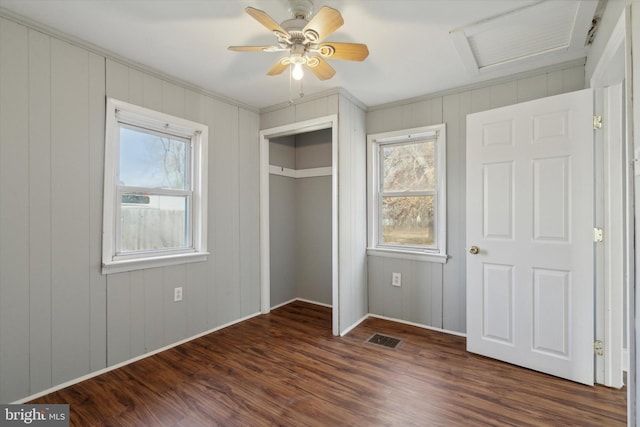 unfurnished bedroom with a closet, dark hardwood / wood-style floors, multiple windows, and ceiling fan