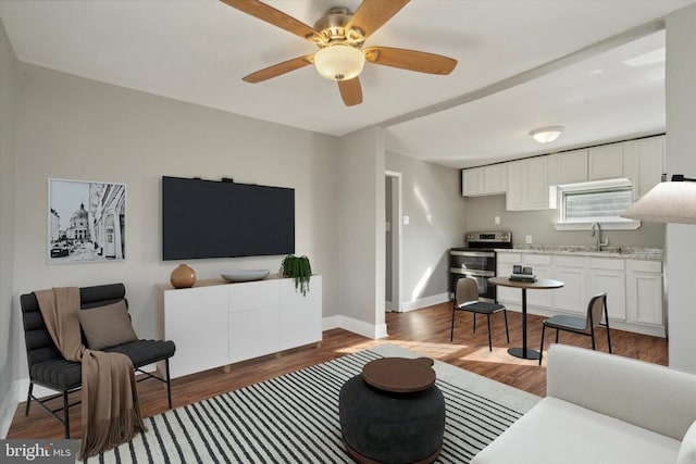 living room featuring ceiling fan, sink, and dark hardwood / wood-style floors