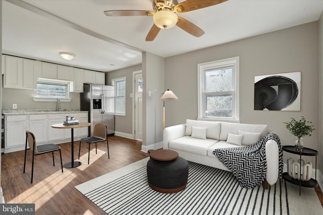 living room with ceiling fan, sink, and dark wood-type flooring