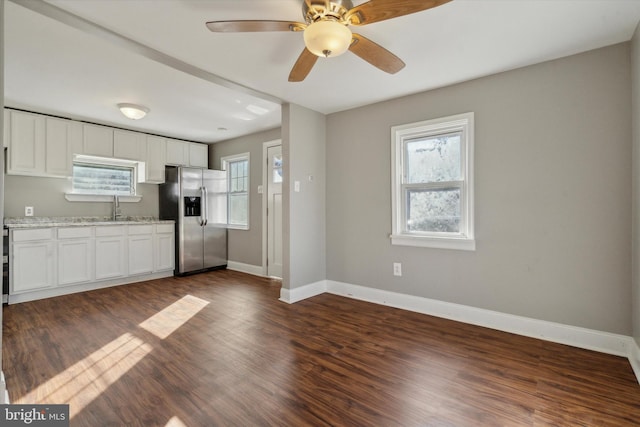 kitchen featuring light stone countertops, sink, dark hardwood / wood-style flooring, stainless steel fridge, and white cabinets