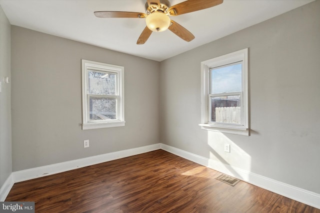 empty room with plenty of natural light, ceiling fan, and dark wood-type flooring