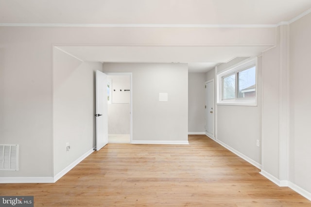 empty room with ornamental molding and light hardwood / wood-style flooring