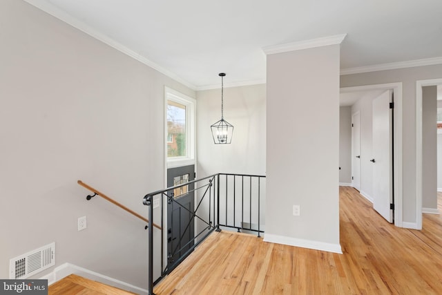 stairway with hardwood / wood-style flooring, crown molding, and an inviting chandelier