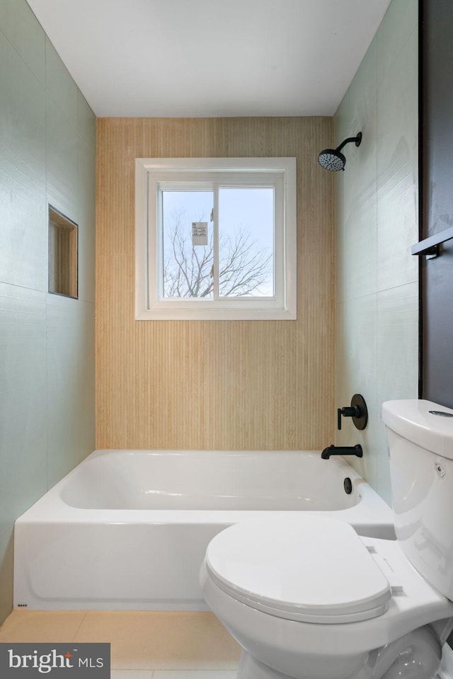 bathroom featuring tile patterned flooring, toilet, and tiled shower / bath