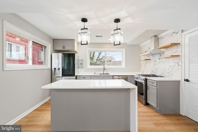 kitchen with sink, stainless steel appliances, light hardwood / wood-style floors, and wall chimney range hood