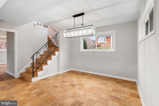 unfurnished dining area featuring light parquet floors, a wealth of natural light, and an inviting chandelier