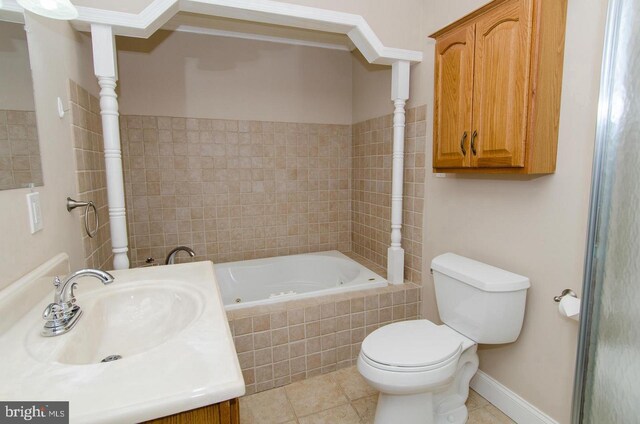 bathroom with tile patterned flooring, vanity, a relaxing tiled tub, and toilet