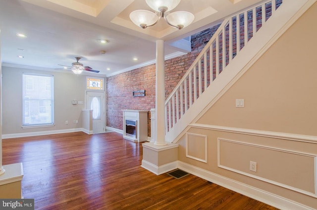 foyer entrance featuring hardwood / wood-style flooring, ornamental molding, and brick wall