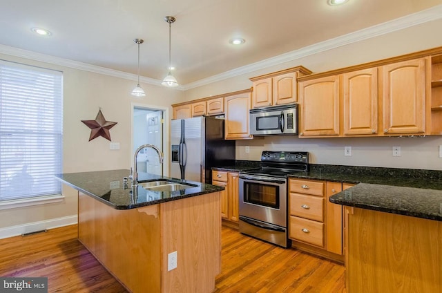 kitchen with a center island with sink, stainless steel appliances, decorative light fixtures, and light wood-type flooring