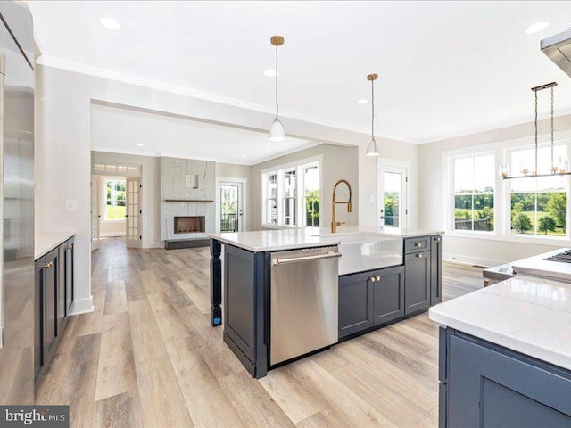 kitchen featuring pendant lighting, a center island with sink, stainless steel dishwasher, and light hardwood / wood-style floors