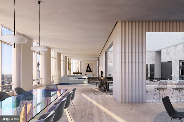 dining space with a wealth of natural light, expansive windows, and light wood-type flooring