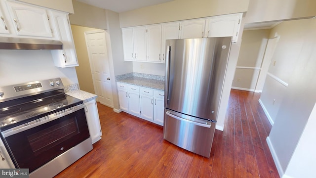 kitchen featuring light stone countertops, dark wood-type flooring, range hood, white cabinets, and appliances with stainless steel finishes