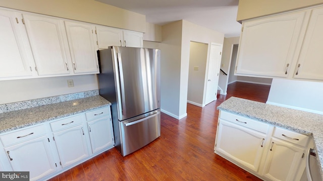 kitchen with white cabinetry, light stone countertops, and stainless steel refrigerator