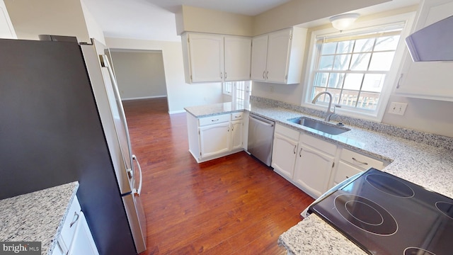 kitchen with white cabinets, stainless steel appliances, light stone counters, and sink