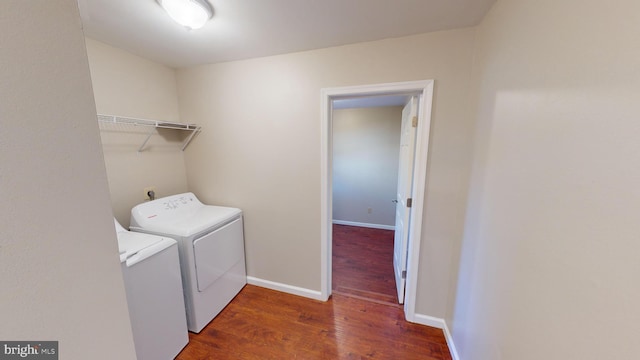 clothes washing area featuring washer and clothes dryer and dark hardwood / wood-style flooring