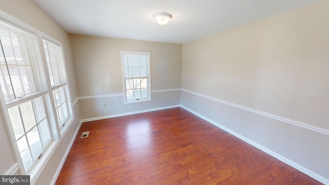 spare room with plenty of natural light and dark hardwood / wood-style floors