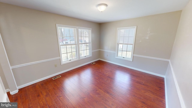 unfurnished room featuring a wealth of natural light and dark wood-type flooring