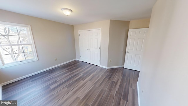 unfurnished bedroom with a closet and dark wood-type flooring