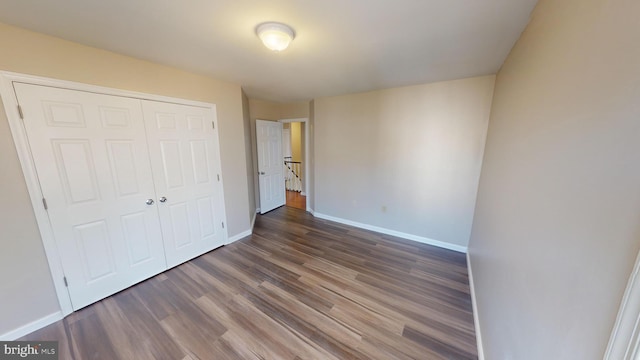 unfurnished bedroom featuring a closet and dark wood-type flooring