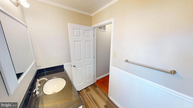 bathroom with hardwood / wood-style floors, ornamental molding, and sink