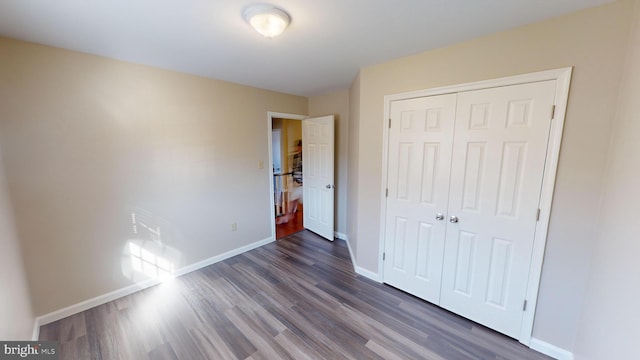 unfurnished bedroom featuring a closet and dark wood-type flooring