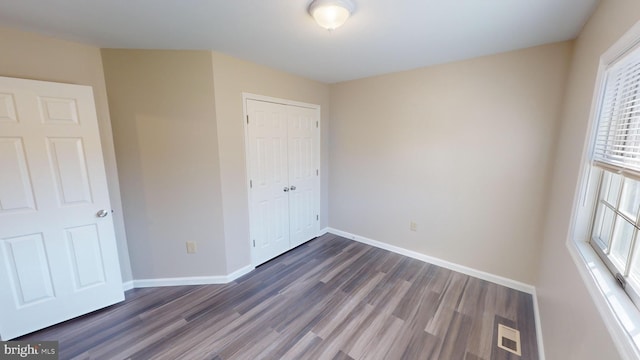 unfurnished bedroom featuring dark hardwood / wood-style floors and a closet