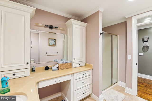 bathroom with tile patterned floors, vanity, a shower with shower door, and ornamental molding