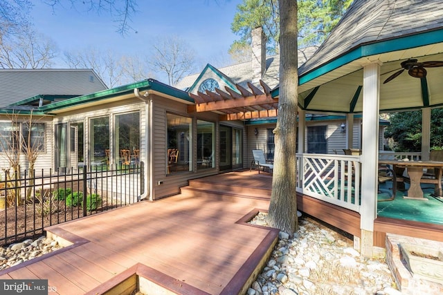 wooden deck featuring ceiling fan and a pergola