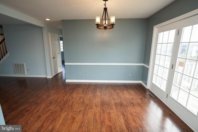 empty room featuring dark wood-type flooring and an inviting chandelier