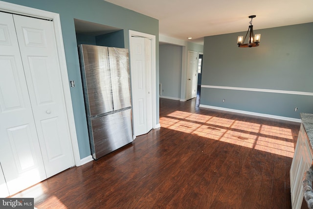 unfurnished dining area featuring a notable chandelier and dark hardwood / wood-style flooring