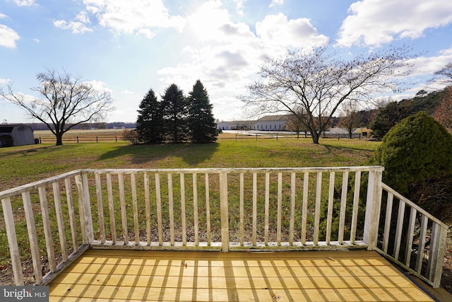 wooden deck with a lawn and a rural view