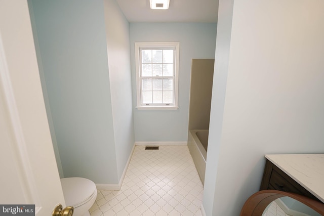 bathroom featuring tile patterned flooring, vanity, a bath, and toilet