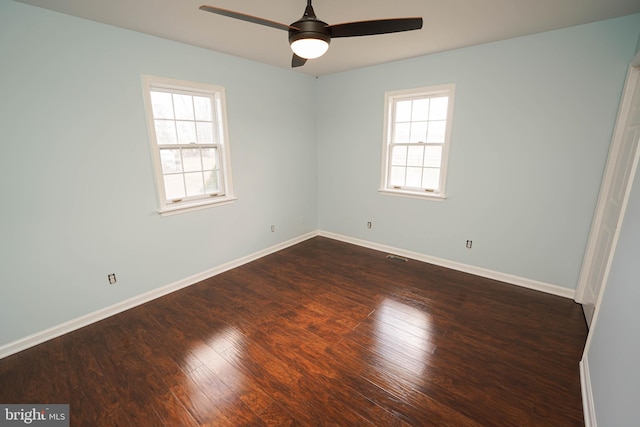 spare room featuring dark wood-type flooring, ceiling fan, and a healthy amount of sunlight