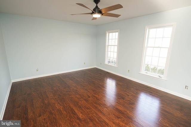 spare room with dark hardwood / wood-style floors, a wealth of natural light, and ceiling fan