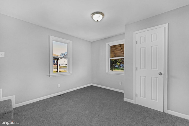 unfurnished room with dark carpet and a healthy amount of sunlight