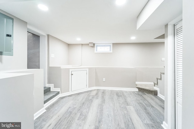 basement featuring electric panel and light hardwood / wood-style floors