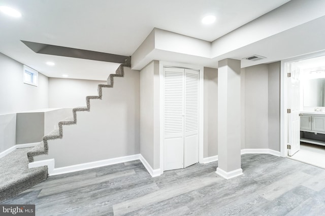 basement with light hardwood / wood-style floors and sink