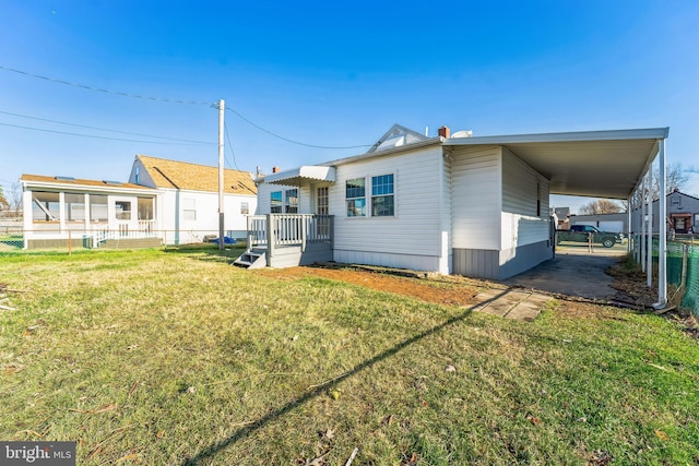 rear view of property with a carport and a lawn