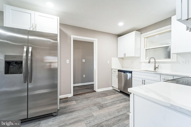 kitchen with white cabinets, sink, stainless steel appliances, and light hardwood / wood-style flooring