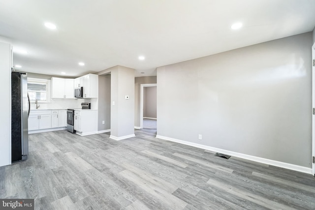 unfurnished living room featuring light hardwood / wood-style flooring and sink