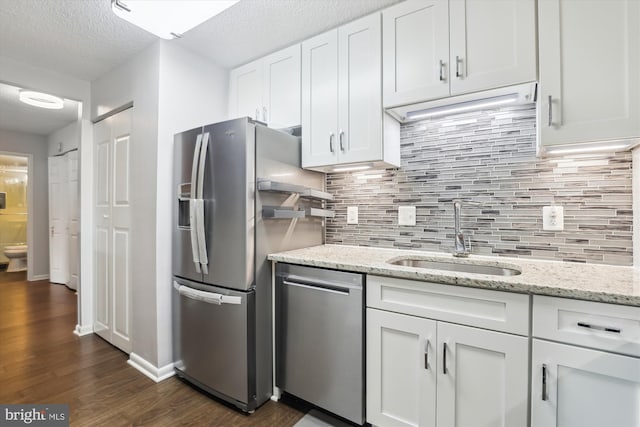 kitchen featuring appliances with stainless steel finishes, a textured ceiling, dark wood-type flooring, sink, and white cabinets