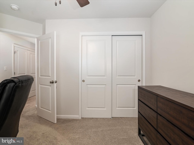 bedroom with ceiling fan, a closet, and light colored carpet