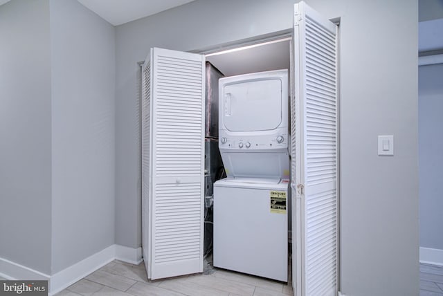 laundry area featuring stacked washer and clothes dryer and light wood-type flooring