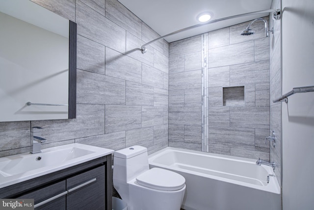 full bathroom featuring vanity, toilet, tiled shower / bath, and tile walls