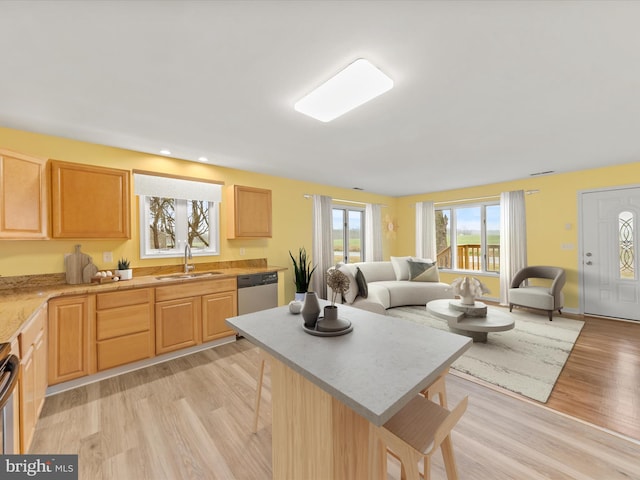 kitchen with sink, light brown cabinets, stainless steel appliances, a kitchen bar, and light wood-type flooring