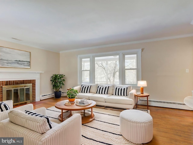 living room with a baseboard heating unit, light wood-type flooring, ornamental molding, and a fireplace