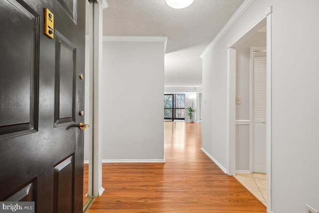 corridor with crown molding, a textured ceiling, and light wood-type flooring